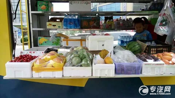 小刘在自己的流动售货车上售卖水果